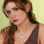 Woman wearing a necklace with a pendant against a light green background