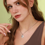 Woman wearing a necklace with a coin pendant against a light green background