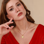 Woman wearing a gold medal necklace with a pendant against a beige background