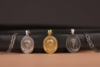Four virgin mary pendants on black leather with a brown background