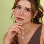 Woman wearing a necklace with a religious pendant against a light green background