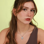 Woman wearing a necklace with a polished silver pendant against a light green background