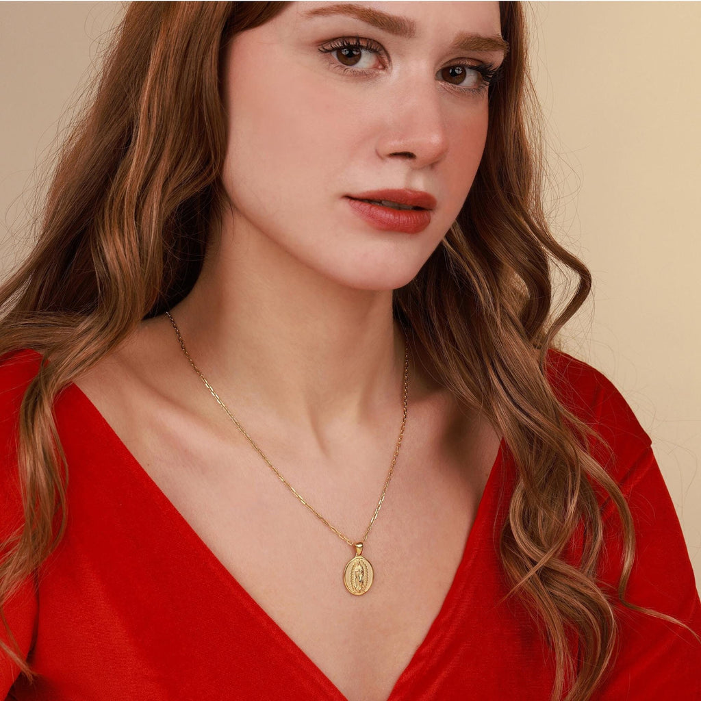 Woman wearing a gold religious necklace with a pendant against a beige background