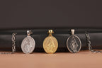 Four virgin mary pendants on chains against a dark background