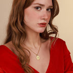 Woman wearing a gold faith necklace with a pendant against a beige background