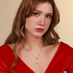Woman wearing a gold jesus necklace with a red top against a beige background