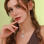 Woman wearing a necklace with a polished pendant against a light green background