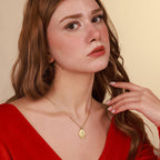 Woman wearing a gold religious necklace against a beige background