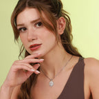 Woman wearing a necklace with a saint pendant against a light green background