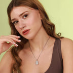 Woman wearing a necklace with a mother mary pendant against a light green background