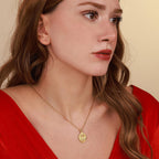 Woman wearing a gold christian necklace with a pendant against a beige background