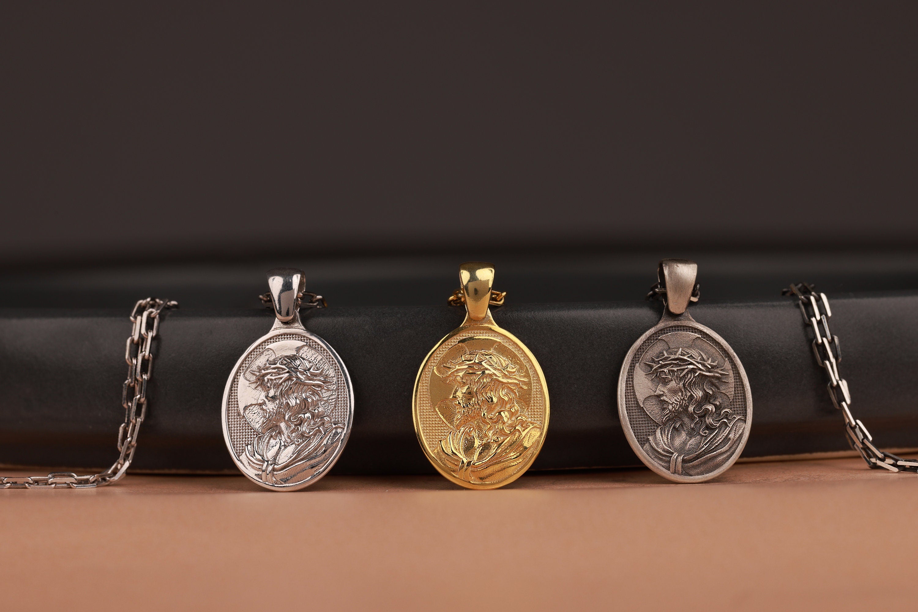 Three Crown of thorn Jesus pendants on a black and brown gradient background