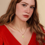 Woman wearing a gold jesus necklace with a pendant against a beige background