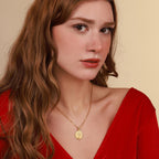 Woman wearing a gold saint michael necklace with a pendant against a beige background