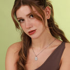 Woman wearing a necklace with a religious pendant against a green background