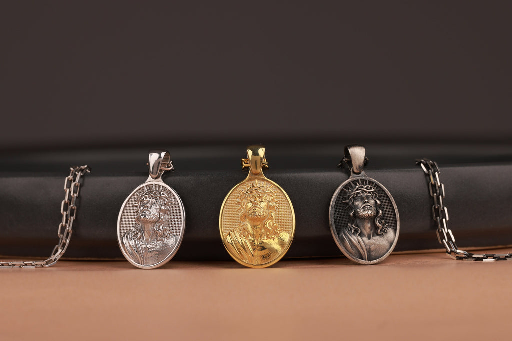 Three jesus pendants on a black cylindrical object with a brown background