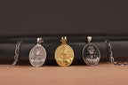 Three jesus pendants on a black cylindrical object with a brown background
