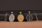 Three different Mary Undoer of Knots pendants on chains against a dark background