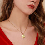 Close-up of a woman wearing a gold necklace with a jesus pendant, against a neutral background.