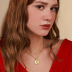 Woman wearing a gold necklace with a virgin mary pendant against a beige background