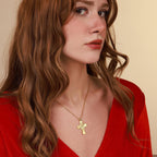 Woman wearing a gold vermeil necklace with a jesus cross pendant against a beige background