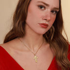 Woman wearing a gold vermeil necklace with a resurrection cross pendant against a beige background