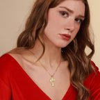 A gold inri cross pendant necklace worn by a woman with red dress