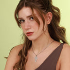 Woman wearing a polished silver jesus cross necklace against a light green background