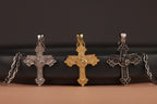 Three St Michael the Archangel cross pendants on chains against a dark background
