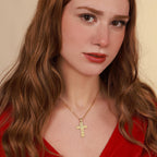 Woman wearing a gold necklace with a rose cross pendant against a beige background
