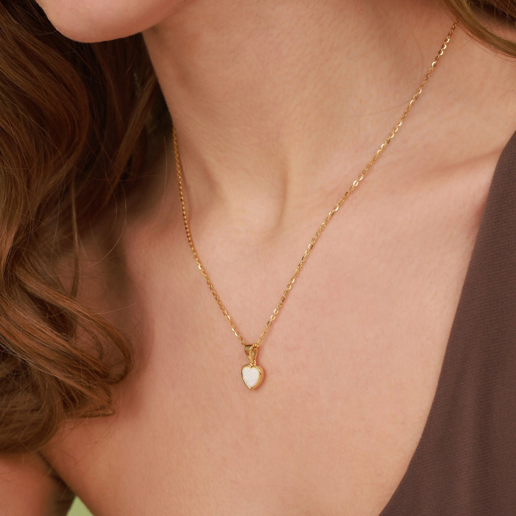Gold necklace with a heart-shaped pendant worn by a person