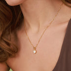 Gold necklace with a heart-shaped pendant worn by a person