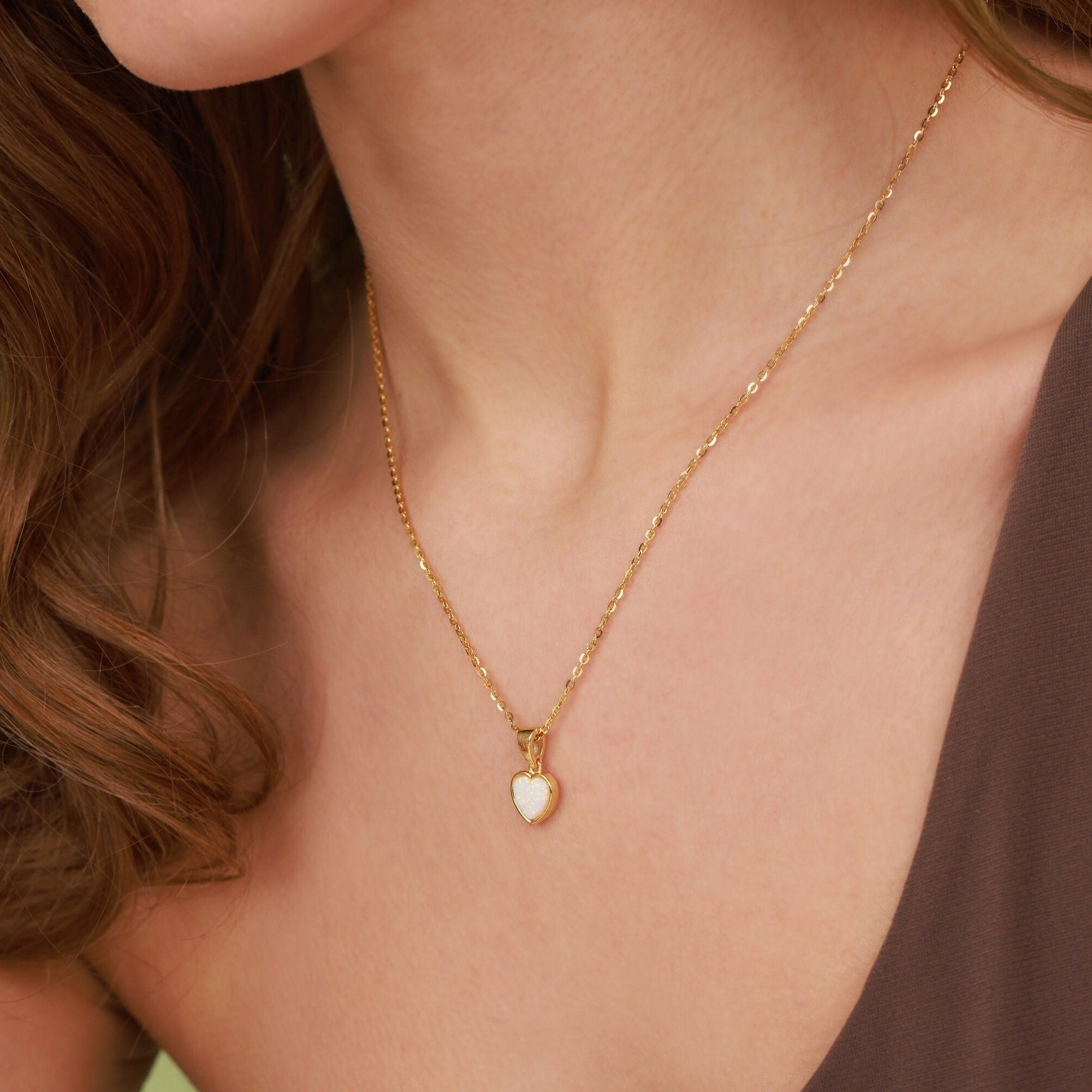 Gold necklace with a heart-shaped pendant worn by a person