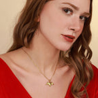 Woman wearing a gold necklace with a bat pendant against a neutral background