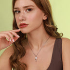 Woman wearing a necklace with an origami seahorse pendant against a light green background