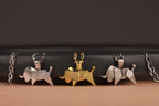 Three origami taurus bull pendants on chains against a black background