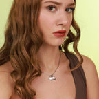 Woman wearing a necklace with a minimalist pendant against a yellow background