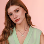 Woman wearing a light green top and  necklace with a pink background
