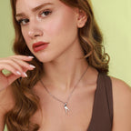 Woman wearing a necklace with a small polished bird pendant against a light green background