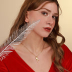 Woman wearing a gold parrot necklace with a feather accessory on a beige background