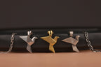 Three bird-shaped pendants on chains against a dark background