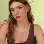 Woman wearing a necklace with a sterling silver bird pendant against a light green background
