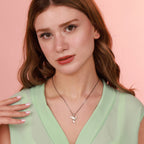 Woman wearing an oxidized silver dove necklace with a pink background