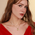Woman wearing a gold necklace with a swallow pendant against a beige background