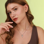 Woman wearing a polished silver hummingbird necklace with a green background