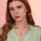 Woman wearing a green top and a sterling silver oxidized rabbit necklace against a pink background