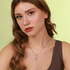 Woman wearing a necklace with a polished flamingo silver pendant against a light green background