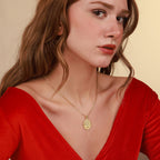 Woman wearing a gold necklace with a tree of life medallion pendant against a beige background