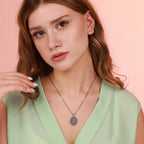 Woman wearing an oxidized silver tree of life necklace against a pink background