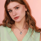 Woman wearing a necklace with a pendant against a pink background